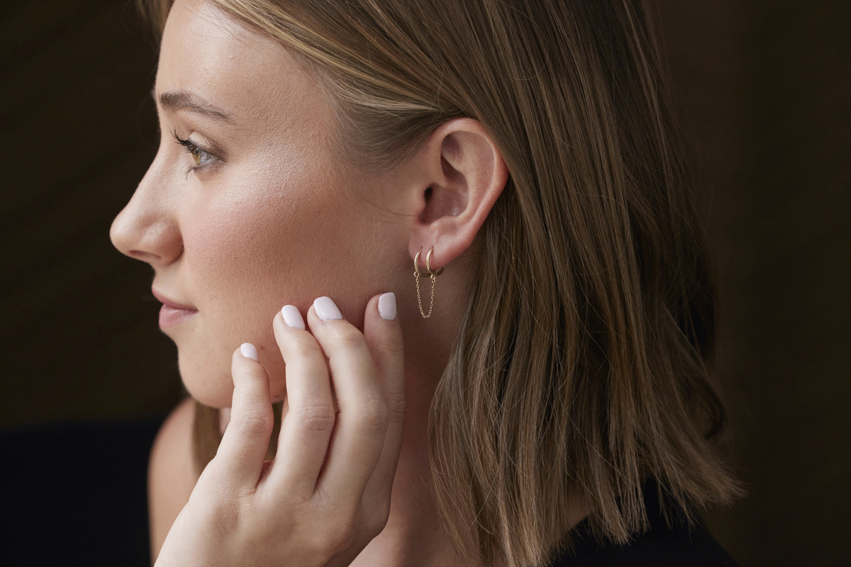 Side profile of model wearing double hoop chain earrings