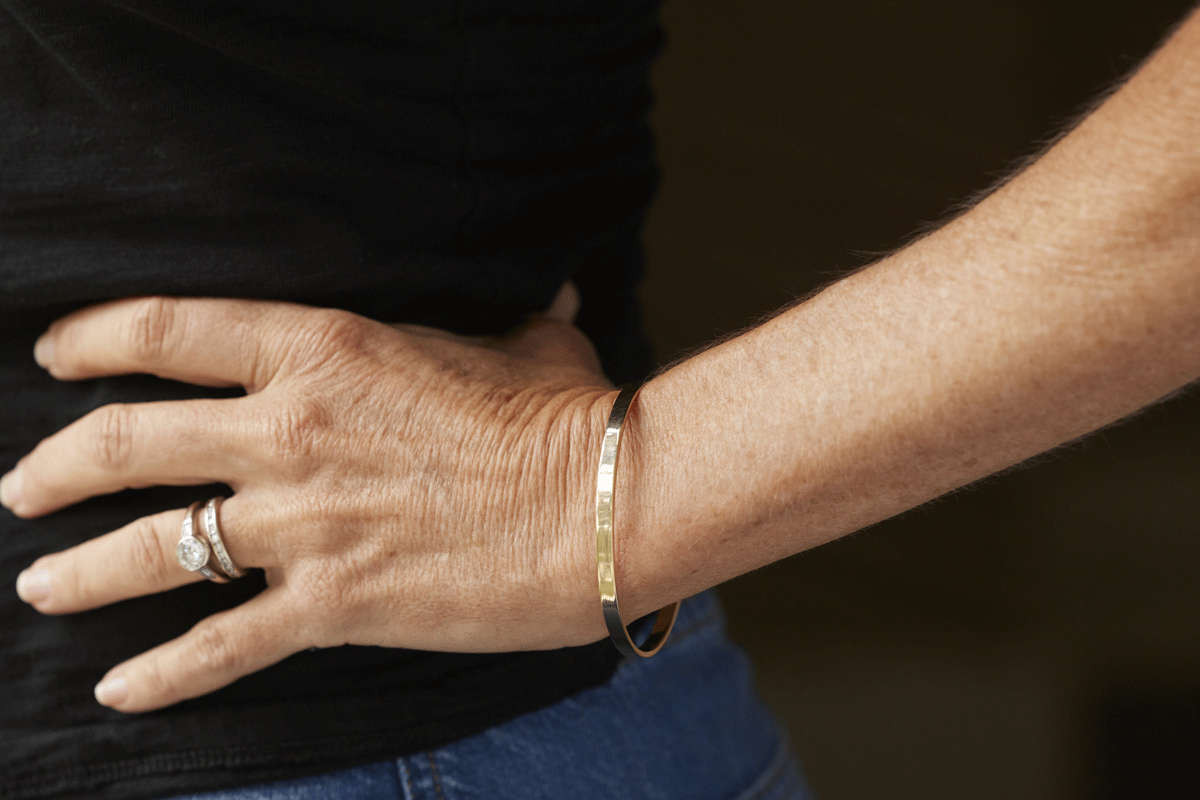 Woman's hand and arm wearing a thick gold bangle bracelet
