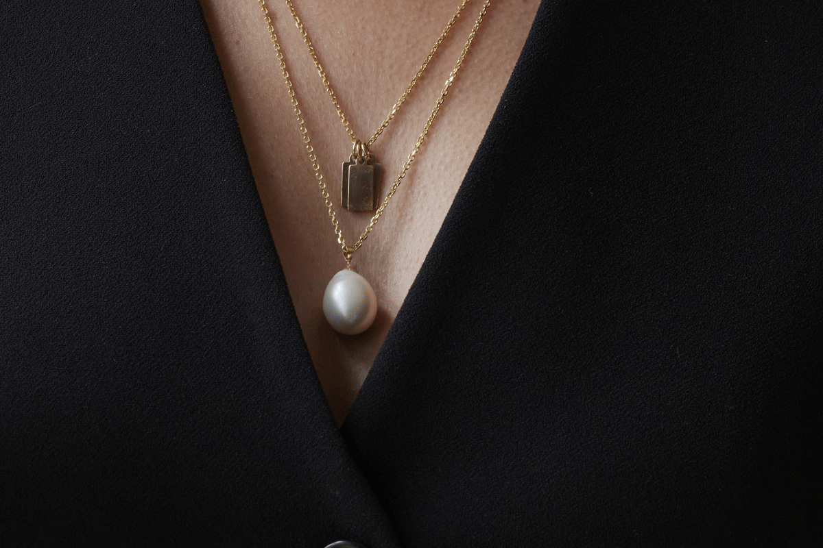 Set of thin gold chain necklaces with pearl charm and gold tags pendant on woman
