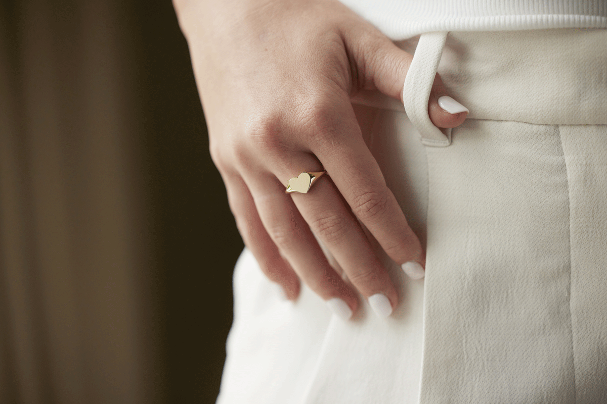Woman's hand with gold signet heart ring