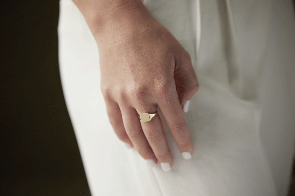 Woman's hand wearing a gold signet heart ring