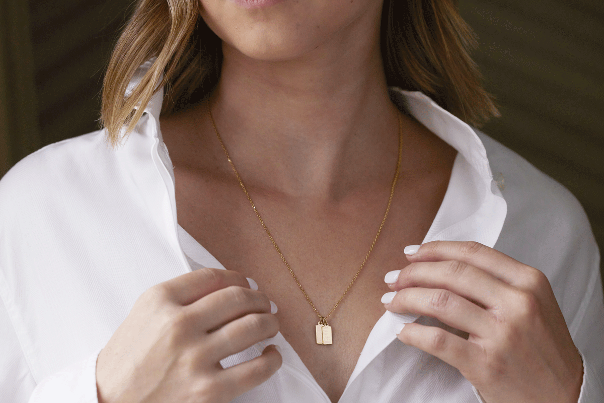 Woman wearing a gold chain with tiny gold tag charms