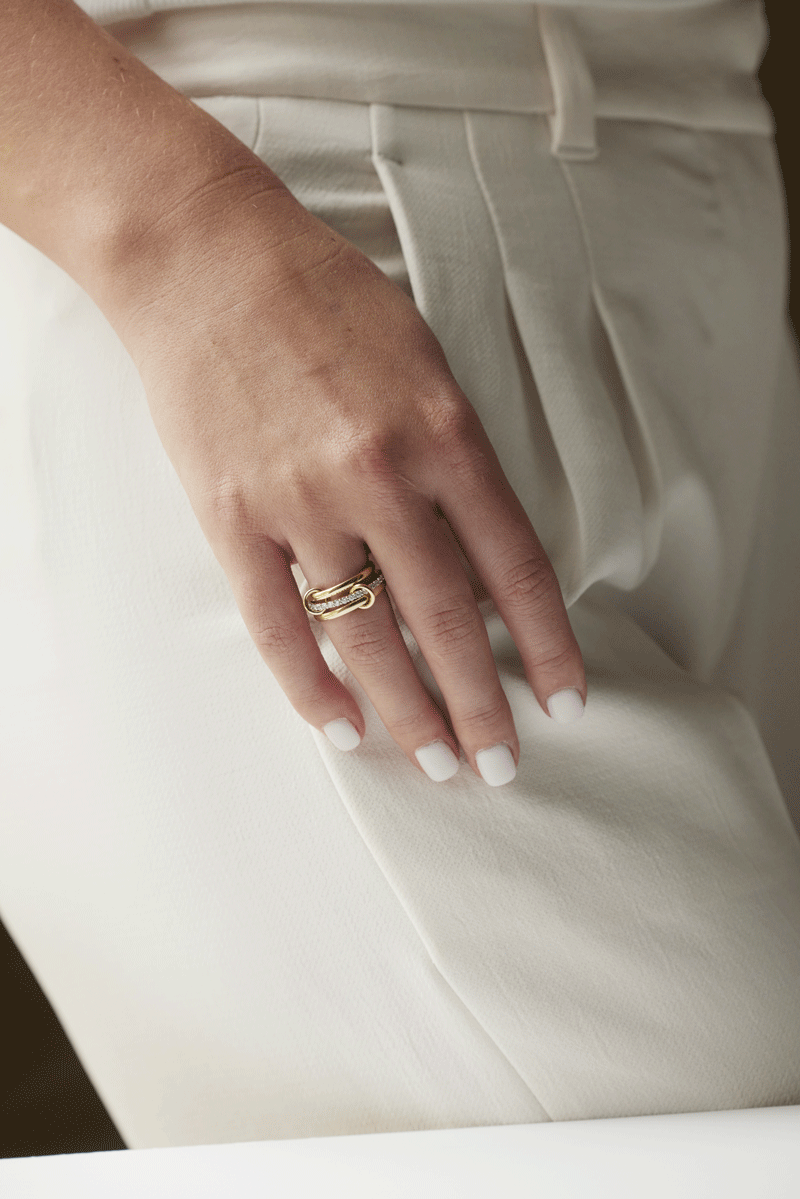 Woman's hand with stacked gold jump rings with diamond ring in the middle