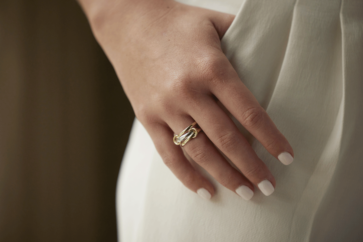 Woman's hand in her pocket wearing a 3-band gold ring with loops