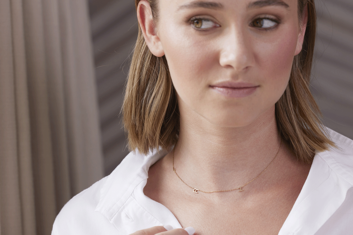 Young girl wearing delicate gold chain necklace with initials