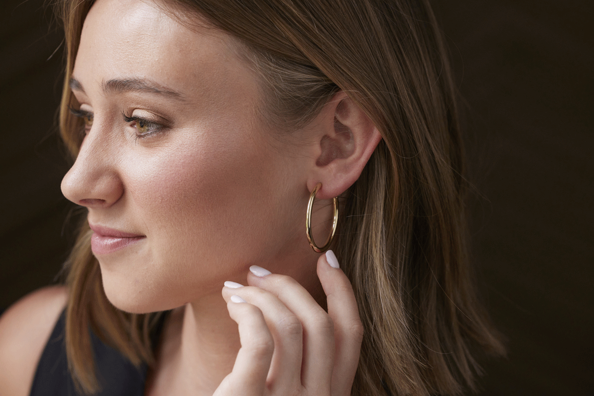 Woman's side profile wearing a large gold hoop earring