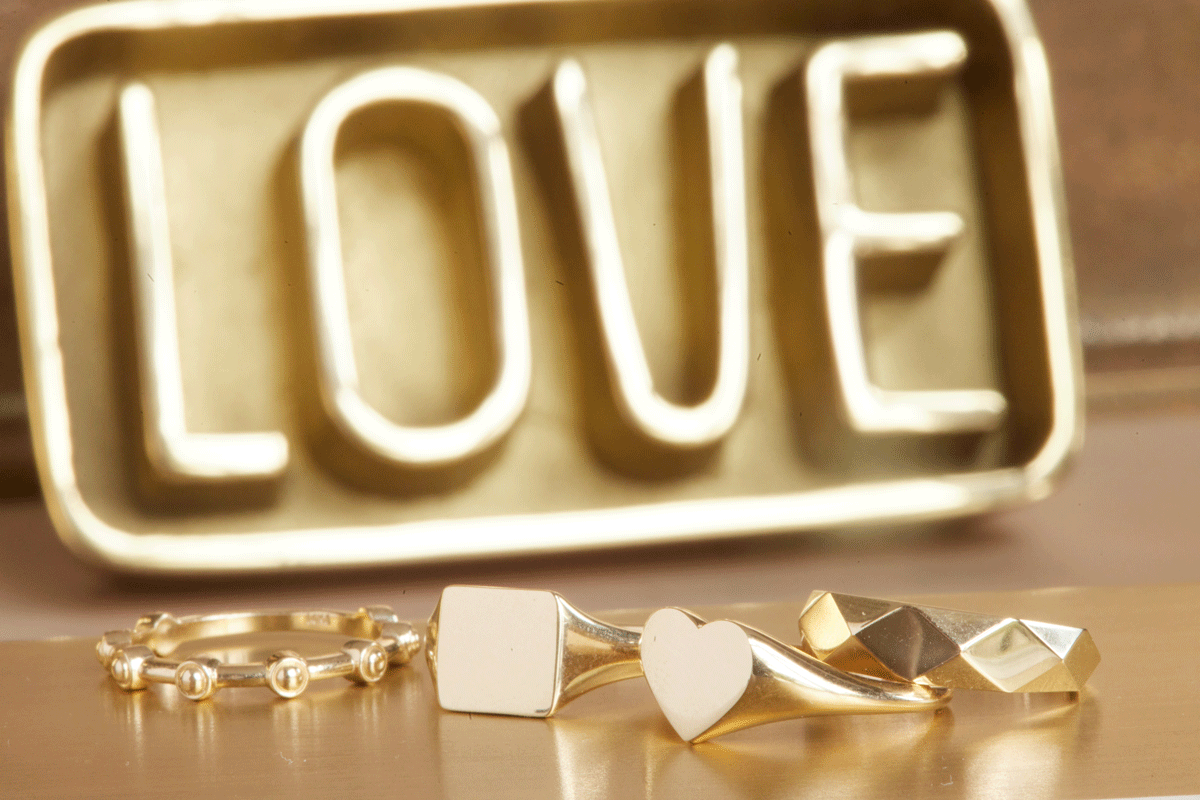 "Love" sign with detail close up of a variety of gold rings in the foreground