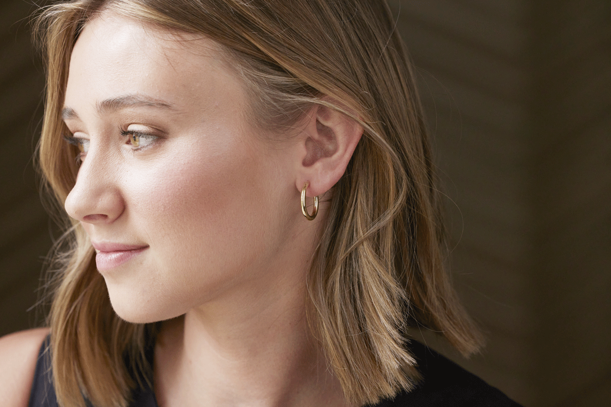 Young adult woman wearing a small gold hoop earring