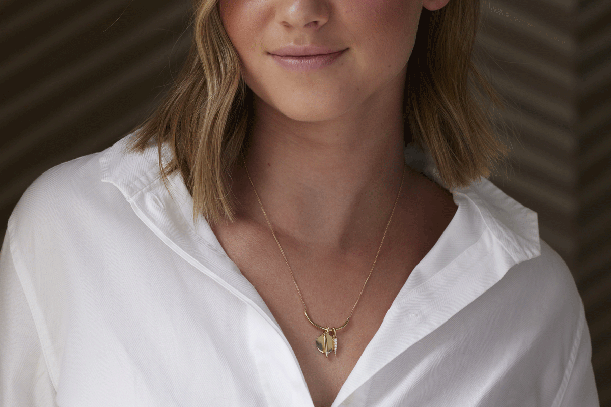 Woman wearing a gold necklace with multiple gold charm pendants
